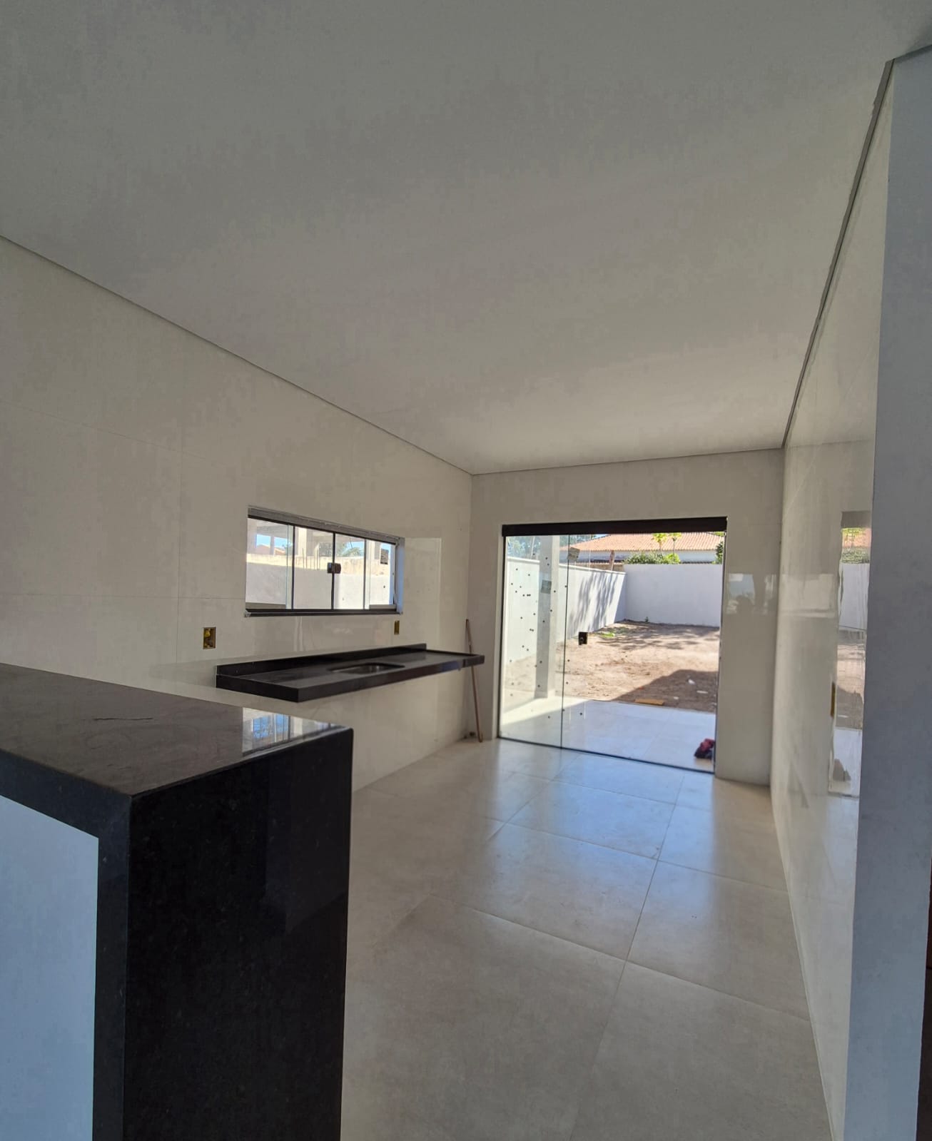 Cozinha com bancada em granito preto e porta de vidro para a área externa