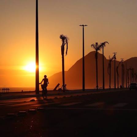 Entardecer na orla de Itaipuaçu com silhuetas de coqueiros