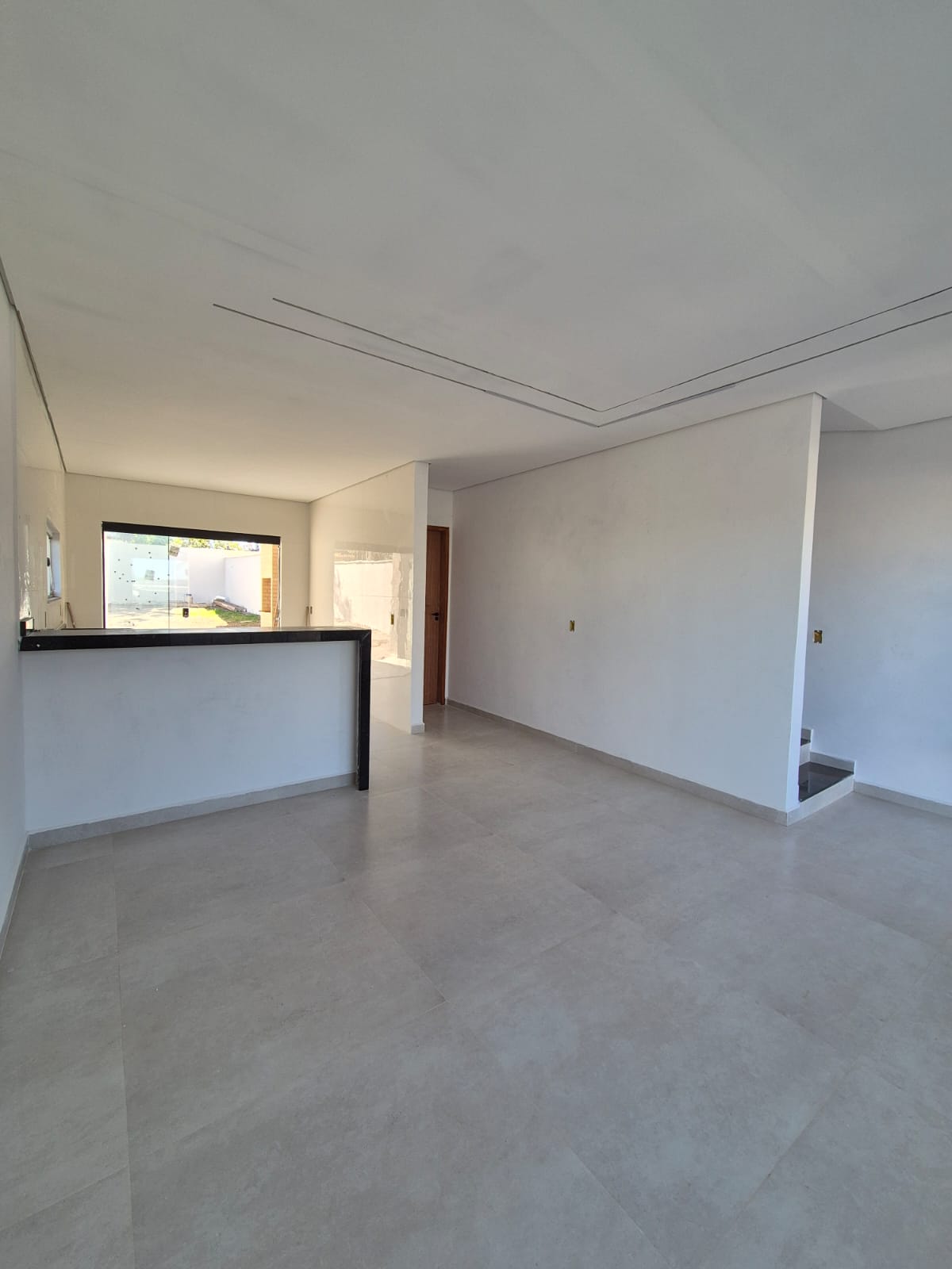 Sala ampla com bancada em granito preto e sanca de gesso