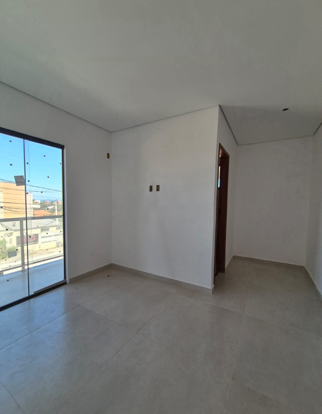 Quarto frontal com porta de vidro para a varanda e piso porcelanato