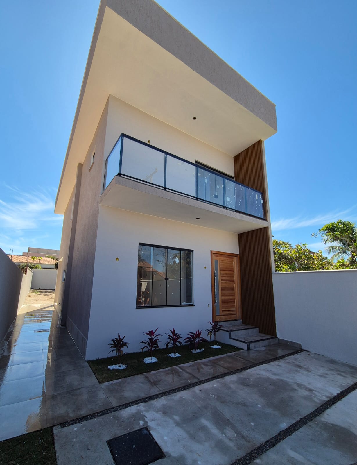 Fachada da casa duplex com varanda em vidro e detalhe ripado em madeira