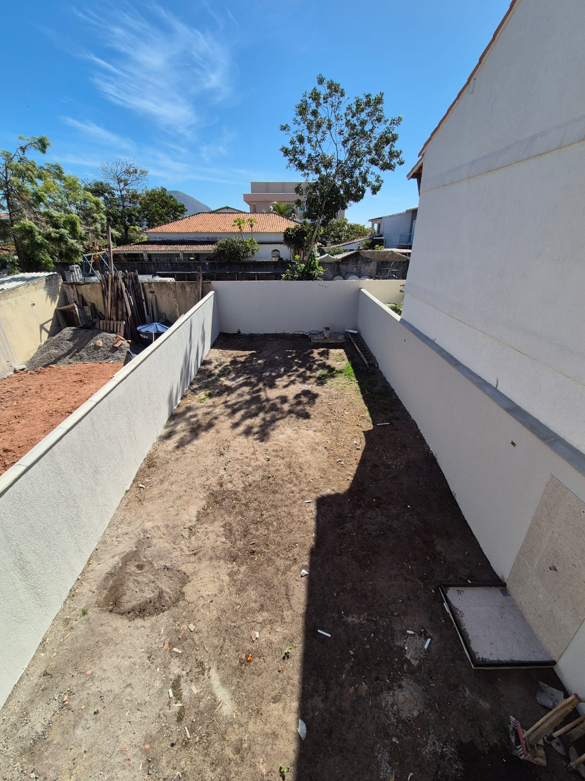 Área externa da casa com piso de concreto e muro alto